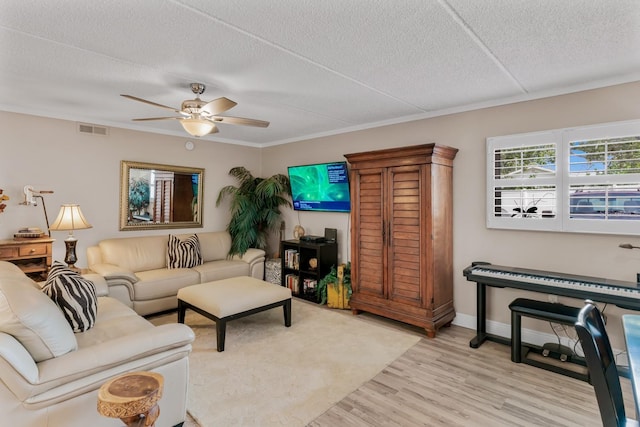 living area with visible vents, a ceiling fan, a textured ceiling, light wood finished floors, and baseboards