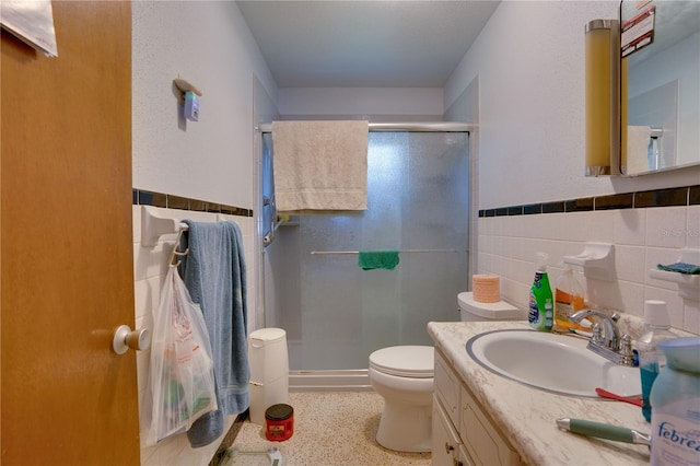 bathroom featuring toilet, a shower with door, vanity, tasteful backsplash, and tile walls