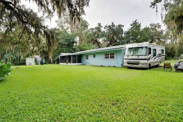 rear view of house featuring a yard and a sunroom