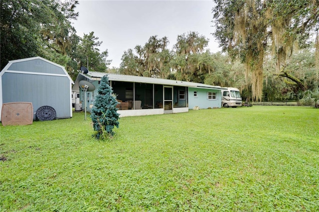 back of house featuring a storage unit, a yard, and a sunroom