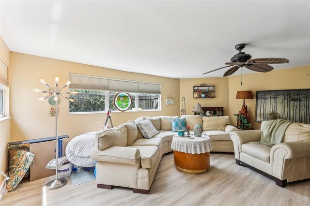 living room with ceiling fan with notable chandelier and light wood-type flooring