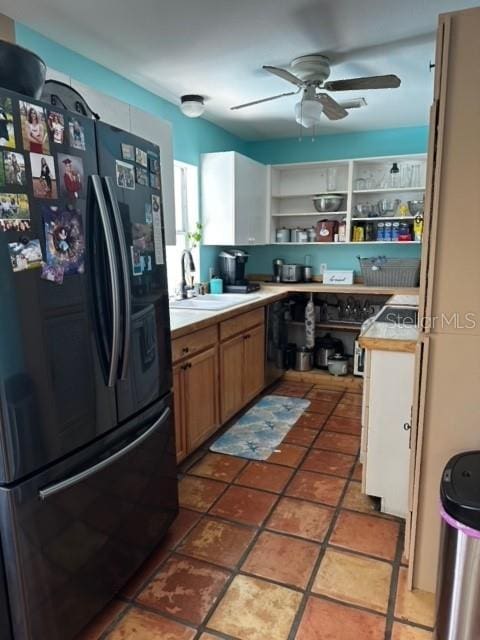 kitchen featuring black fridge, ceiling fan, tile counters, and sink