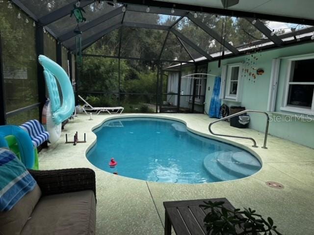 view of swimming pool with glass enclosure and a patio