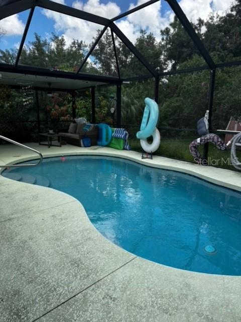 view of pool with glass enclosure and a patio area