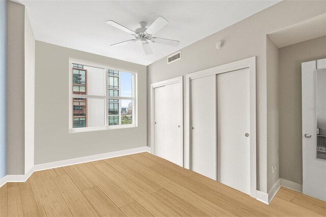 1120 E Kennedy Blvd Unit 734, Tampa, FL 33602 - unfurnished bedroom featuring multiple closets, visible vents, a ceiling fan, wood finished floors, and baseboards