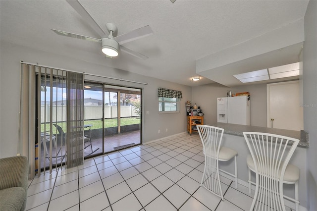 kitchen with ceiling fan, light tile patterned floors, white fridge with ice dispenser, and a textured ceiling