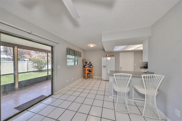 kitchen with white cabinets, light tile patterned floors, and white fridge with ice dispenser