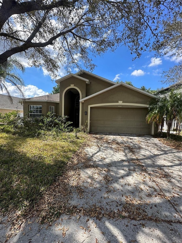 view of front of home with a garage, driveway, and stucco siding