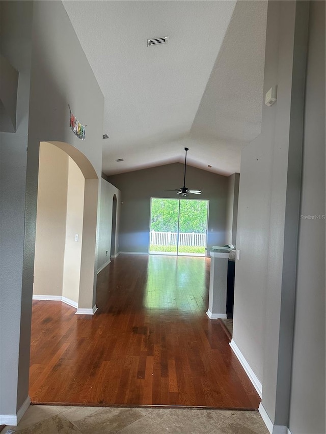 spare room featuring arched walkways, visible vents, vaulted ceiling, wood finished floors, and baseboards