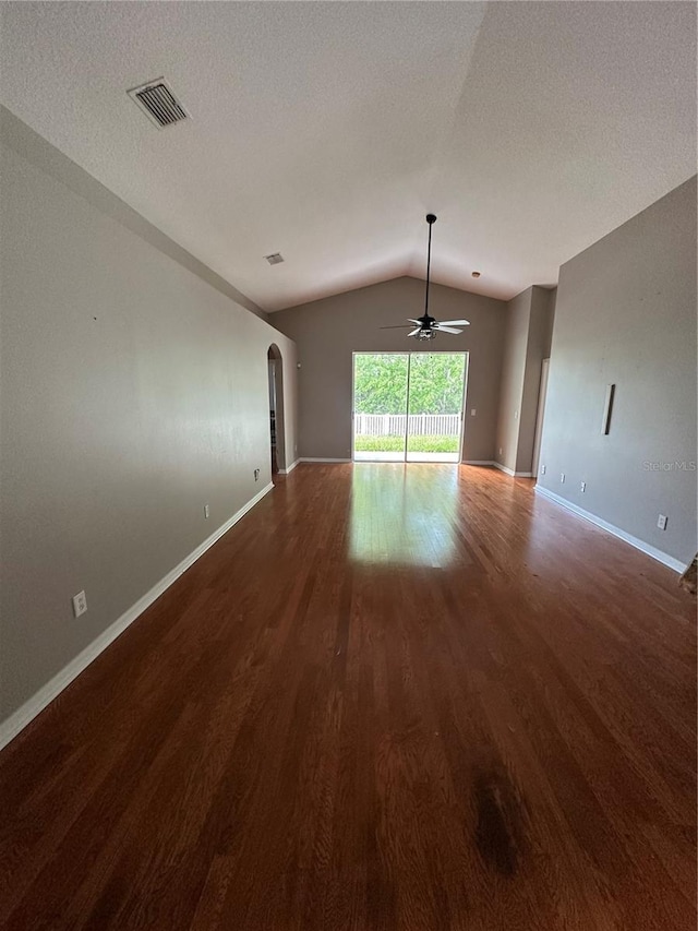 empty room featuring arched walkways, wood finished floors, visible vents, baseboards, and vaulted ceiling