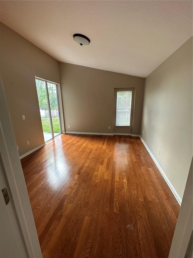 spare room with lofted ceiling, light wood-style floors, and baseboards