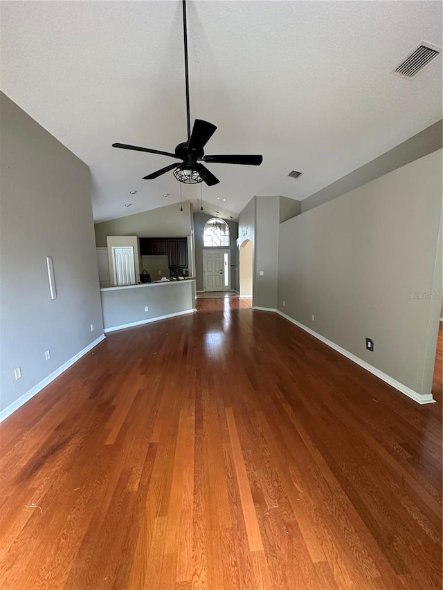 unfurnished living room with visible vents, arched walkways, ceiling fan, wood finished floors, and vaulted ceiling