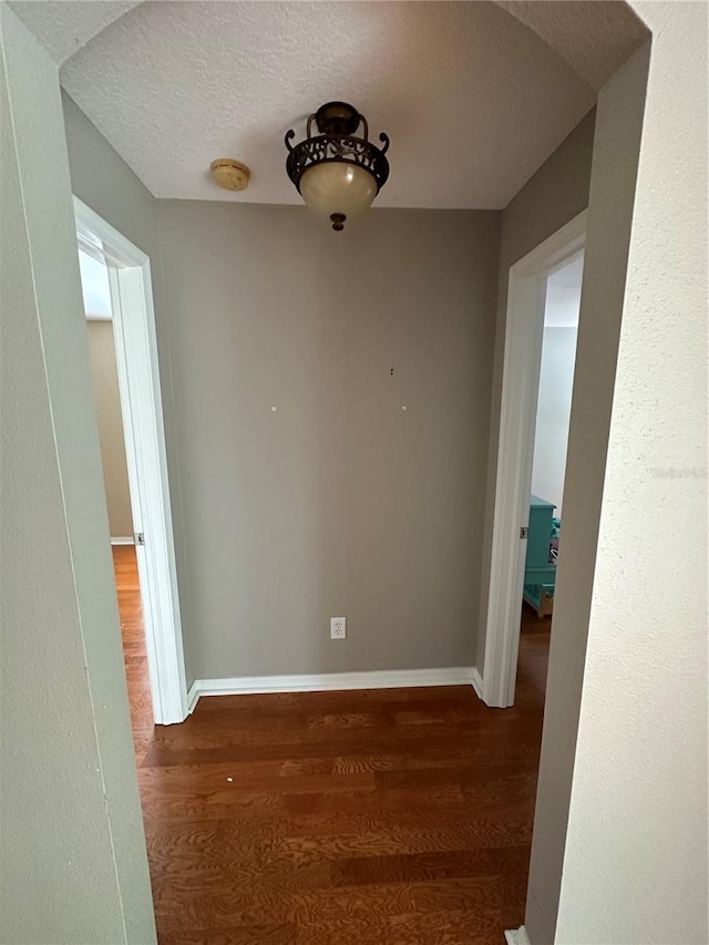 interior space with arched walkways, a textured ceiling, baseboards, and wood finished floors