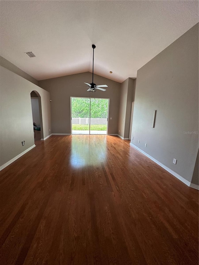 unfurnished living room featuring arched walkways, lofted ceiling, visible vents, wood finished floors, and baseboards