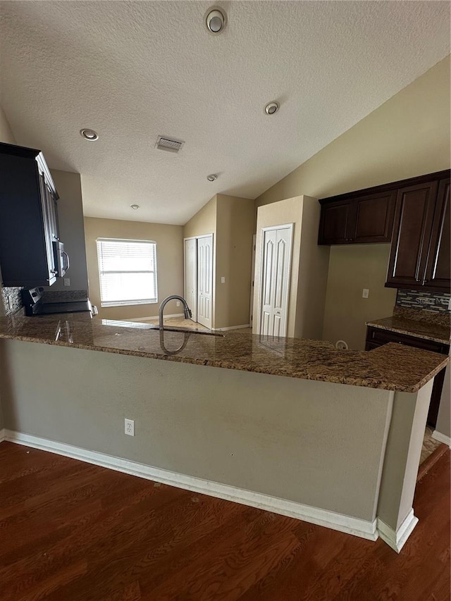 kitchen with vaulted ceiling, appliances with stainless steel finishes, dark stone countertops, and visible vents