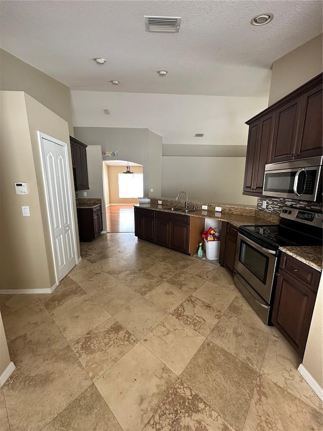 kitchen featuring visible vents, appliances with stainless steel finishes, vaulted ceiling, a sink, and dark brown cabinets