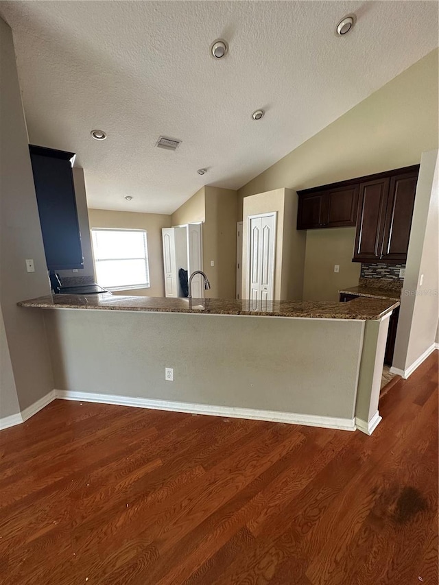 kitchen with dark brown cabinetry, baseboards, visible vents, dark wood-style floors, and vaulted ceiling