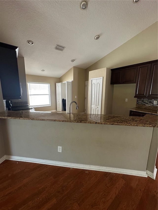 kitchen featuring stone counters, lofted ceiling, visible vents, and wood finished floors