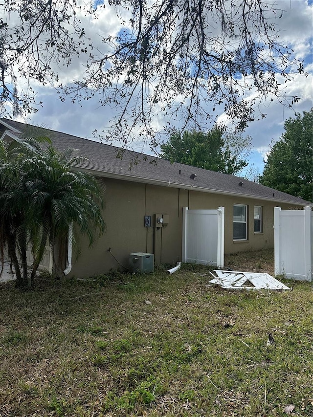 back of house with fence, a lawn, and stucco siding