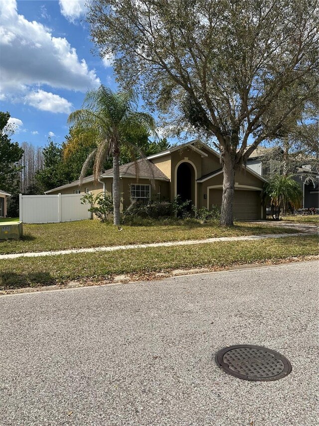 view of front of house featuring an attached garage, fence, and stucco siding