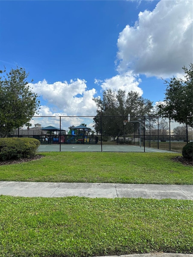 view of property's community with community basketball court, fence, and a yard