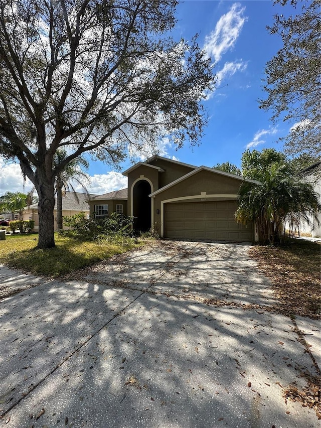 view of front of home with concrete driveway, an attached garage, and stucco siding