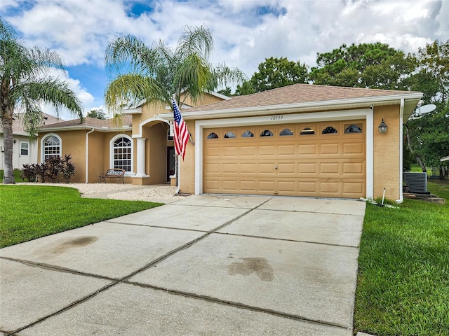 single story home with cooling unit, a garage, and a front lawn