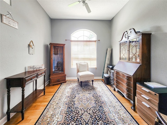 sitting room with ceiling fan, light hardwood / wood-style floors, and a textured ceiling