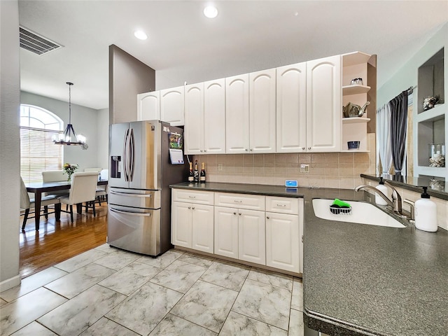 kitchen with pendant lighting, an inviting chandelier, sink, stainless steel refrigerator with ice dispenser, and light hardwood / wood-style floors