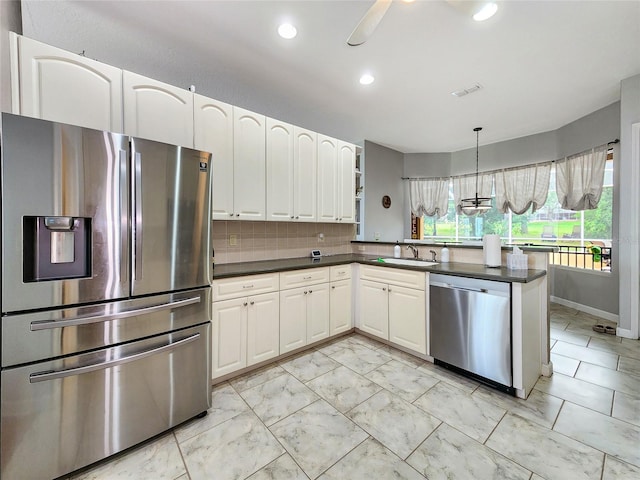 kitchen with appliances with stainless steel finishes, ceiling fan, kitchen peninsula, pendant lighting, and decorative backsplash