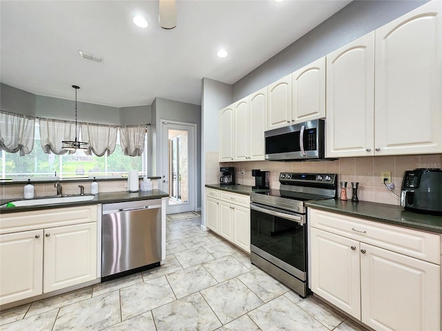 kitchen with pendant lighting, stainless steel appliances, sink, and backsplash