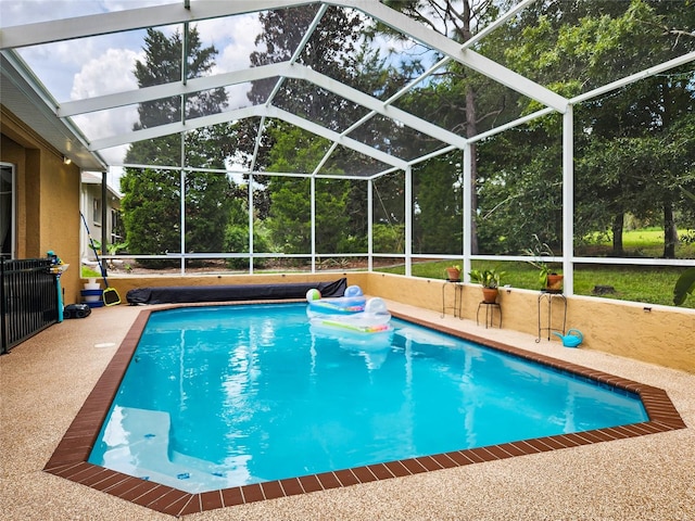 view of pool with glass enclosure and a patio area