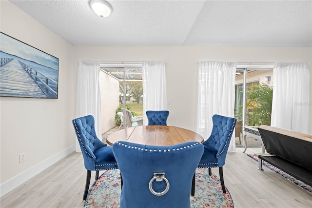 dining room featuring a textured ceiling and light wood-type flooring