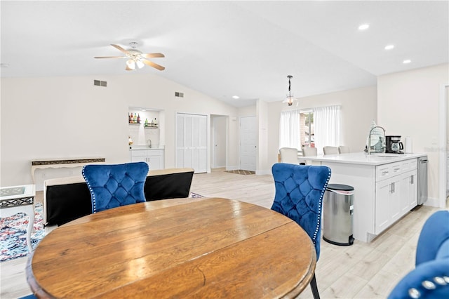 dining room featuring sink, light hardwood / wood-style flooring, ceiling fan, and vaulted ceiling