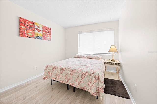 bedroom with light hardwood / wood-style floors and a textured ceiling