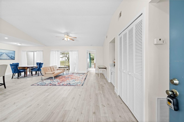 living room with lofted ceiling, ceiling fan, and light wood-type flooring