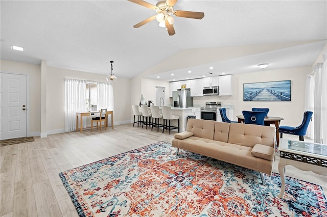 living room featuring ceiling fan, sink, vaulted ceiling, and light hardwood / wood-style flooring