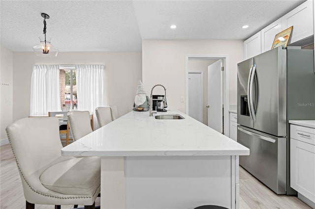 kitchen with pendant lighting, stainless steel fridge, and an island with sink