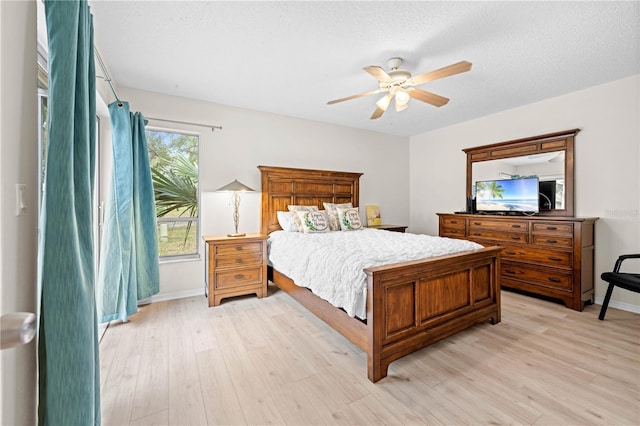 bedroom with light wood-type flooring, a textured ceiling, and ceiling fan