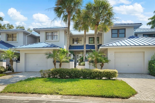 view of front facade with a standing seam roof, stucco siding, decorative driveway, and metal roof