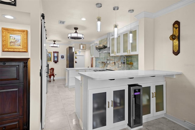 kitchen featuring decorative backsplash, visible vents, light countertops, a peninsula, and glass insert cabinets