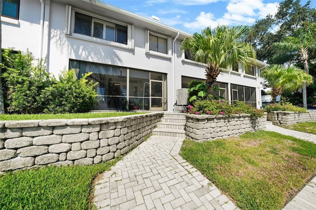 rear view of property with a sunroom and stucco siding