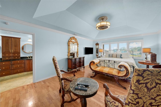 bedroom with ornamental molding, lofted ceiling, ensuite bathroom, a tray ceiling, and light wood finished floors