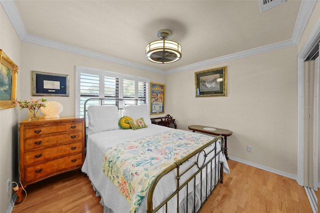 bedroom with visible vents, ornamental molding, light wood-style floors, and baseboards