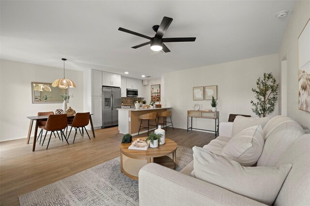 living room featuring ceiling fan and light hardwood / wood-style floors