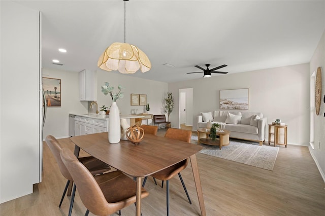 dining area featuring light wood-type flooring, ceiling fan, and sink