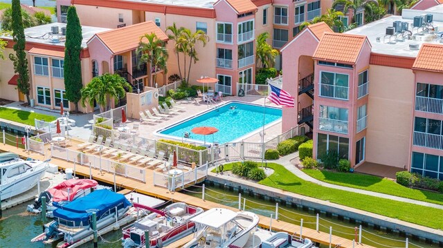 view of swimming pool with a water view, a boat dock, and a patio