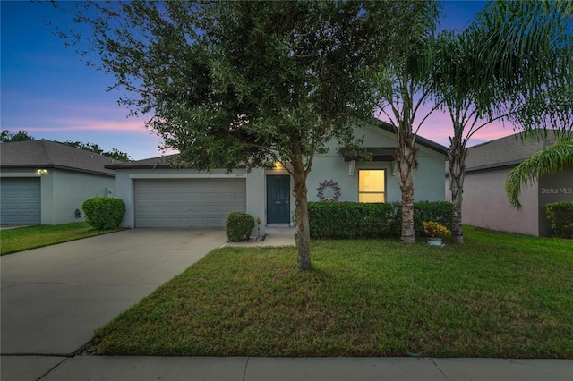 single story home with a garage and a lawn