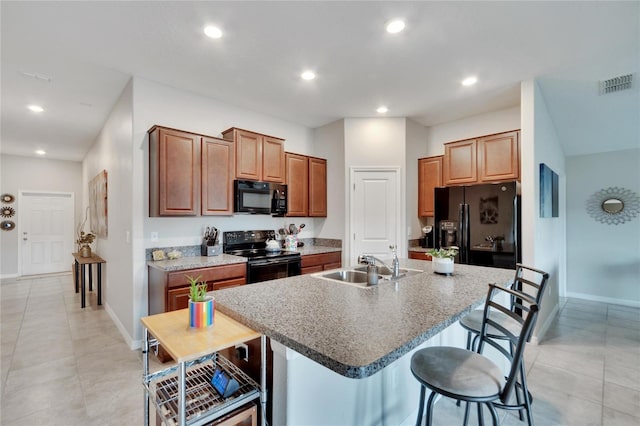 kitchen featuring a kitchen breakfast bar, an island with sink, sink, black appliances, and light tile patterned floors