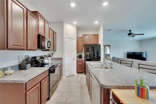 kitchen featuring a center island with sink, sink, black appliances, light tile patterned floors, and ceiling fan